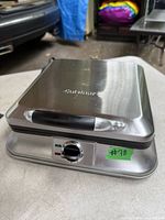 Closed view showing stainless steel body, Cuisinart logo on top, black handle, control dial, and indicator lights on front panel.