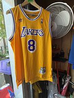Front view of yellow Lakers basketball jersey showing Adidas logo, NBA logo, Lakers text, and number 8.