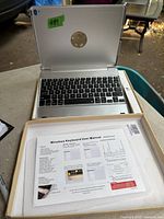 Wireless keyboard integrated into a silver case designed for an iPad, shown in its packaging with user manual.