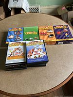 Top view showing eight boxed Carry On DVD sets and stacked individual Carry On DVDs on a round table.