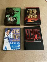 Top view of all four DVDs showing covers for Wizard of Oz, Gone with the Wind, Elvis That's The Way It Is, and Elvis 68 Comeback Special.