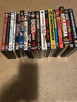 Photo showing 19 wrestling DVDs lined up, including WWE and WCW titles featuring famous wrestlers such as Brock Lesnar, Hulk Hogan, Ultimate Warrior, Andre the Giant, and others.