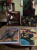 Wide view of King Kong items on round table including boxed figure, battling game, and two posters.