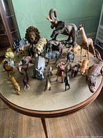 Large collection of various animal figurines including a woolly mammoth, lions, giraffes, tigers, crocodiles, and others arranged on a table.