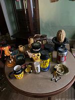 Assorted Mr. Peanut collectibles including mugs, jars, figurines, bowls, and novelty items arranged on a round table
