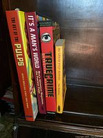 Four hardcover books about pulp and true crime arranged vertically on a wooden shelf.