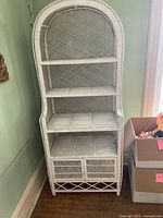 Full view of the white rattan wall unit showcasing arched top, shelves, and cabinet.