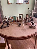Wide view of entire collection on a round table, showing various figurines in different themes: martial arts, cowboys, sports, animals, and human characters.