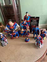 Full view of the collection on a table including several Superman figurines, banks, and cookie jar bust