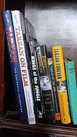 Bookshelf with eight different Tarzan related books standing upright and showing spines