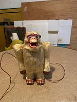Front view of the vintage battery operated yeti toy standing on a textured surface, showing the full figure with fur and detailed face.