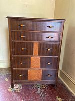 Front view showing five drawers with mixed wood panels and unique handles.