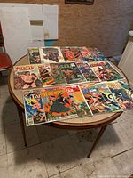 Wide view of 14 vintage Tarzan comic books on round table showing colorful covers in protective sleeves.