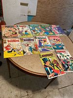 Photo showing all 11 vintage comic books laid out on a round table, titles visible including Popeye, Blondie, Felix the Cat, Mighty Mouse, and Mandrake.