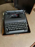 Front view of Smith Corona portable typewriter in case showing keyboard, keys with round shape and visible brand name on top right.