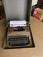 Vintage Underwood portable typewriter in open travel case from front angle, paper loaded with visible typed text.