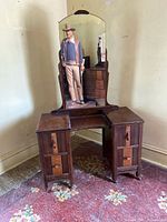 Front view of vintage wooden vanity with mirror and four drawers.