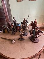 Overview photo showing all figurines and the tomahawk laid out on a table, various Western and knight themes visible