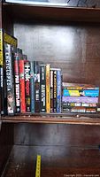 Photo of 18 wrestling books arranged on a wooden shelf, showing spines and some covers with wrestler names and titles.