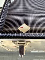 Interior of aluminium trunk showing black-and-white checkered fabric lining and red "22" tag