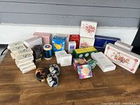 Full frontal photo of multiple Avon products including boxed perfumes, soaps, and other cosmetic containers arranged on a wooden surface.