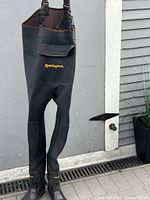 Full view of Remington chest waders hanging, showing front pocket and boots.