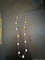 Full view of the necklace showing the white pearls spaced along the fine gold chain.