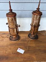 Pair of mica table lamps with metal framing, conical finials, and electrical cords visible.