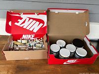 Two Nike shoe boxes containing multiple oil paint tubes and jars labeled Akua