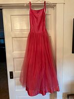 Front view of the dress hanging on a hanger, showing full length with satin bodice and tulle skirt.