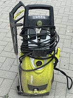 Front angled view of the Ryobi pressure washer showing the control panel, hose wrapped around the front, and attached wand.