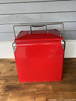Closed view of red metal cooler with chrome handle and rounded corners