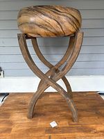 Front view of large wooden salad bowl resting on wooden crossed leg stand