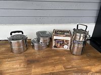 Photo showing all stainless steel lunch boxes and boxed thermal container on a wooden surface