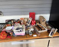 Overview of various Asian inspired items arranged on a table including bowls, textiles, wooden containers and bamboo utensils.