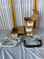 Eight door pull handles, two clear anodized and six bronze anodized, with packaging boxes visible.