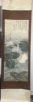 Full view of the hanging scroll showing water lily painting with calligraphy above, mounted on brown silk fabric.