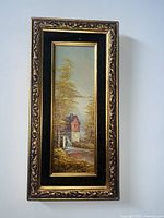 Framed vertical oil painting on board depicting a watermill by a river with trees and a light sky.