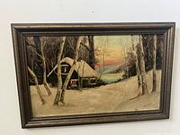 Full front view of the framed winter landscape painting showing a traditional cottage and trees covered with snow.