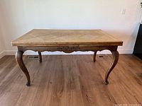 Wooden dining table viewed from front showing carved apron and cabriole legs