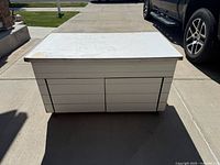 Front view of the sand box showing the table top and storage cabinet doors below.