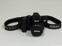 Front view of the Nikon Coolpix P500 camera with Nikon branded lens cap and strap visible.