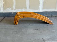 Side profile view of two yellow steel car ramps stacked on each other showing curved incline structure and worn paint areas.