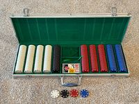 Poker chip set inside open aluminum case with four colors of poker chips arranged in rows on a green felt interior.