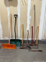 Full view of lot showing snow shovels, rake, axe, splitting maul, sledge hammer, bolt cutters, machete and collapsible trash container.