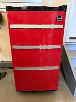 Front exterior view of the red RCA mini fridge showing the tool chest style with three silver handles and RCA logo.
