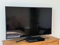 Samsung 60 inch UHD TV and Samsung Blu-ray/DVD player on wood furniture