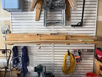 Shelf with stacked scrap lumber including different sizes of wood boards and dowels