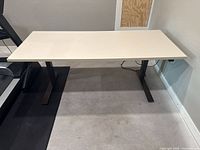 Front view of desk showing white top and black frame.