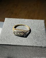 Front and top view of the ring on black surface showing overall design and diamond placement